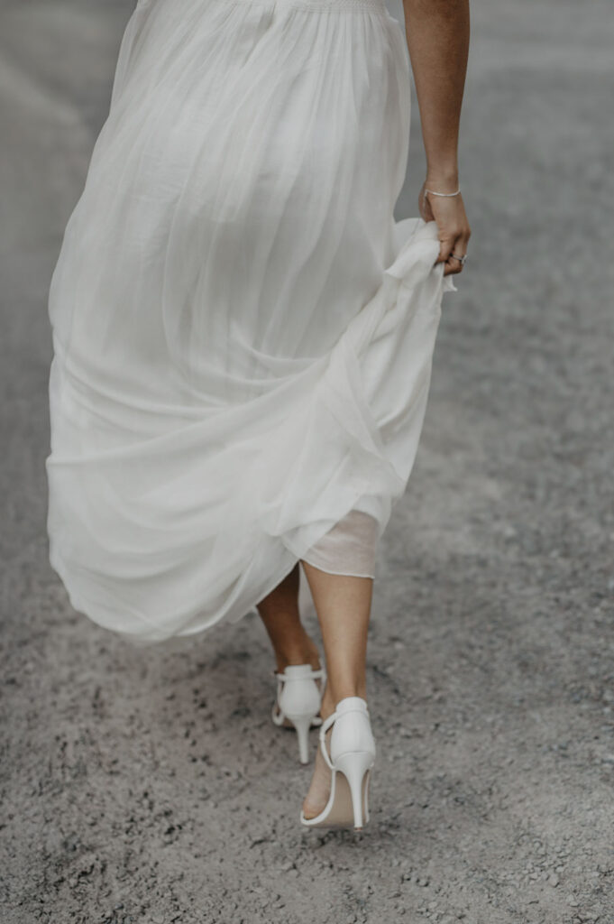 Braut laeuft mit Kleid und High Heels durch Steinbruch in NRW