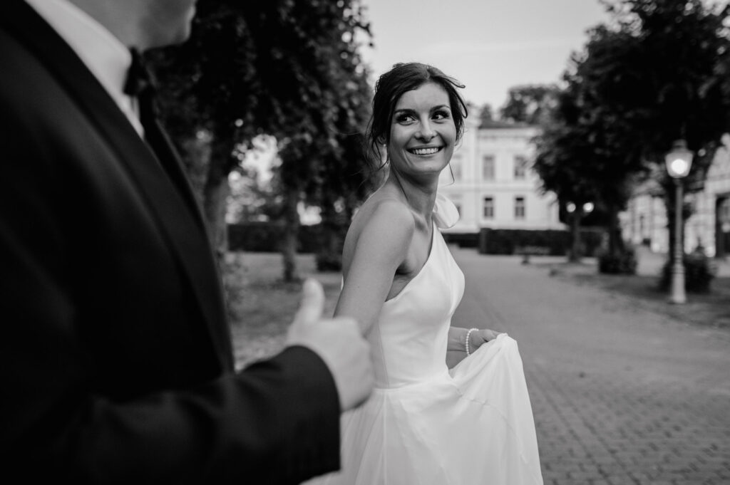 Braut im modernen Hochzeitskleid blickt lachend zu Bräutigam