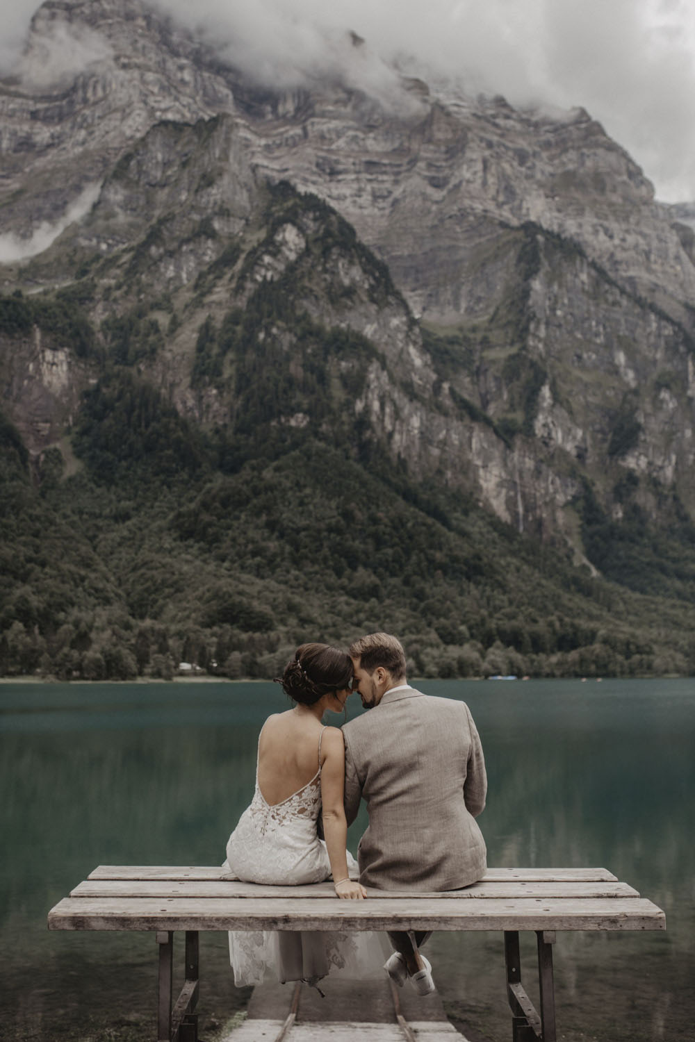 Brautpaar sitzt auf Holzbank am Klöntalersee