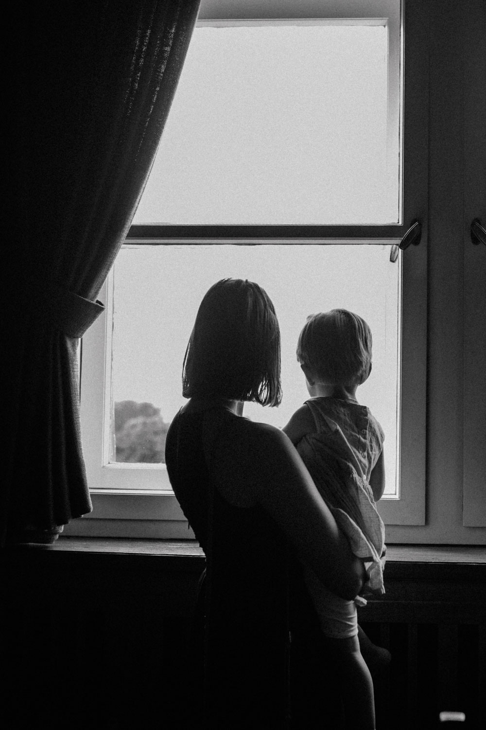 Braut mit Kind blickt aus dem Fenster im Standesamt