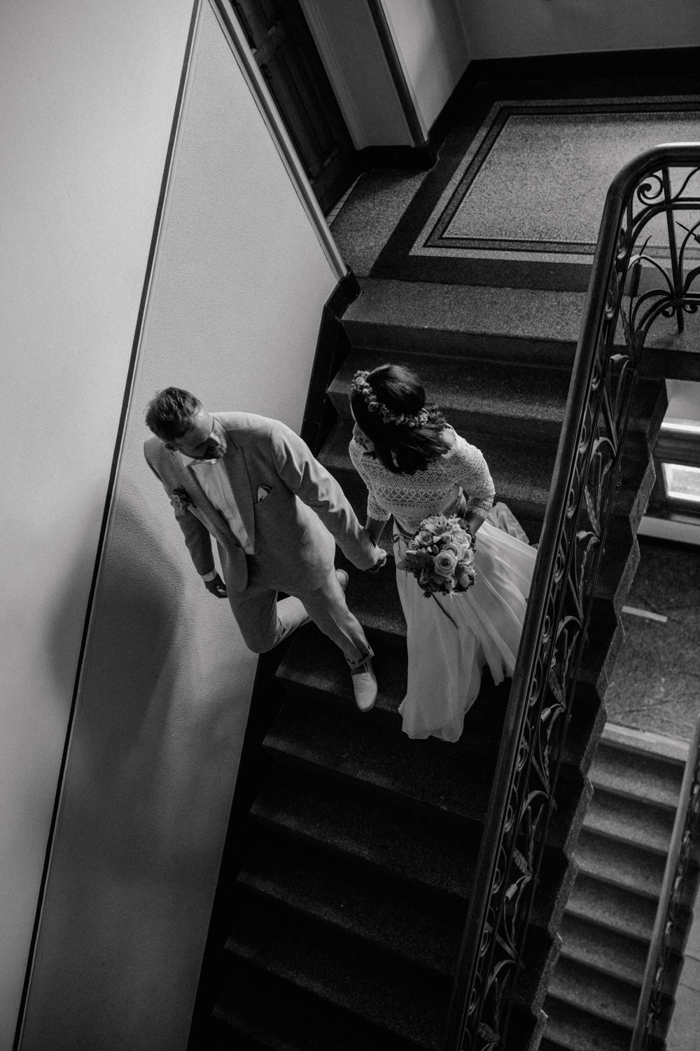 Brautpaar geht Hand in Hand durchs Treppenhaus