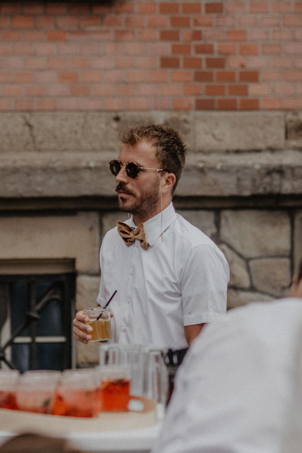 Mann mit Fliege hält Drink in der Hand