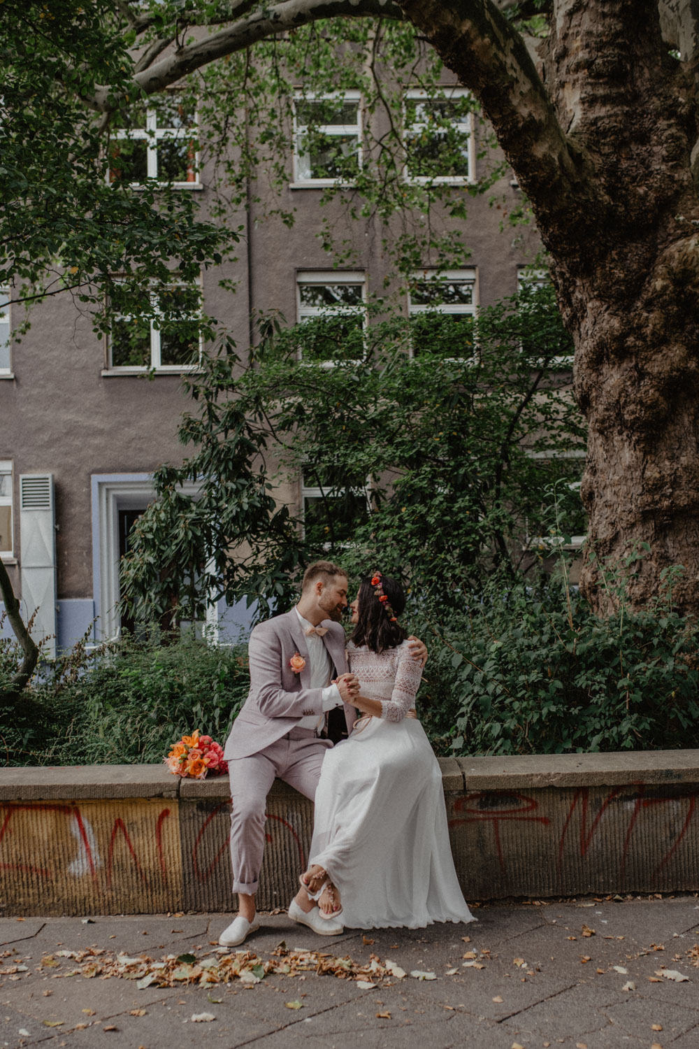 Brautpaar sitzt unter Baum in der Stadt
