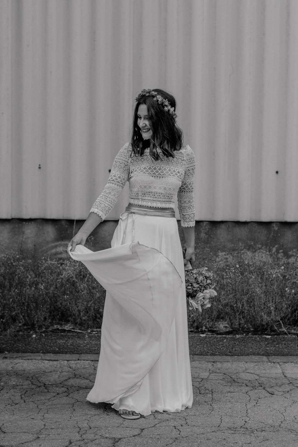 Braut im Boho-Kleid hält ihr Kleid hoch