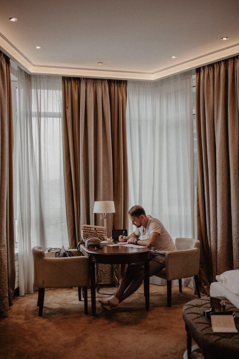 Bräutigam sitzt am Fenster und schreibt im Hotel