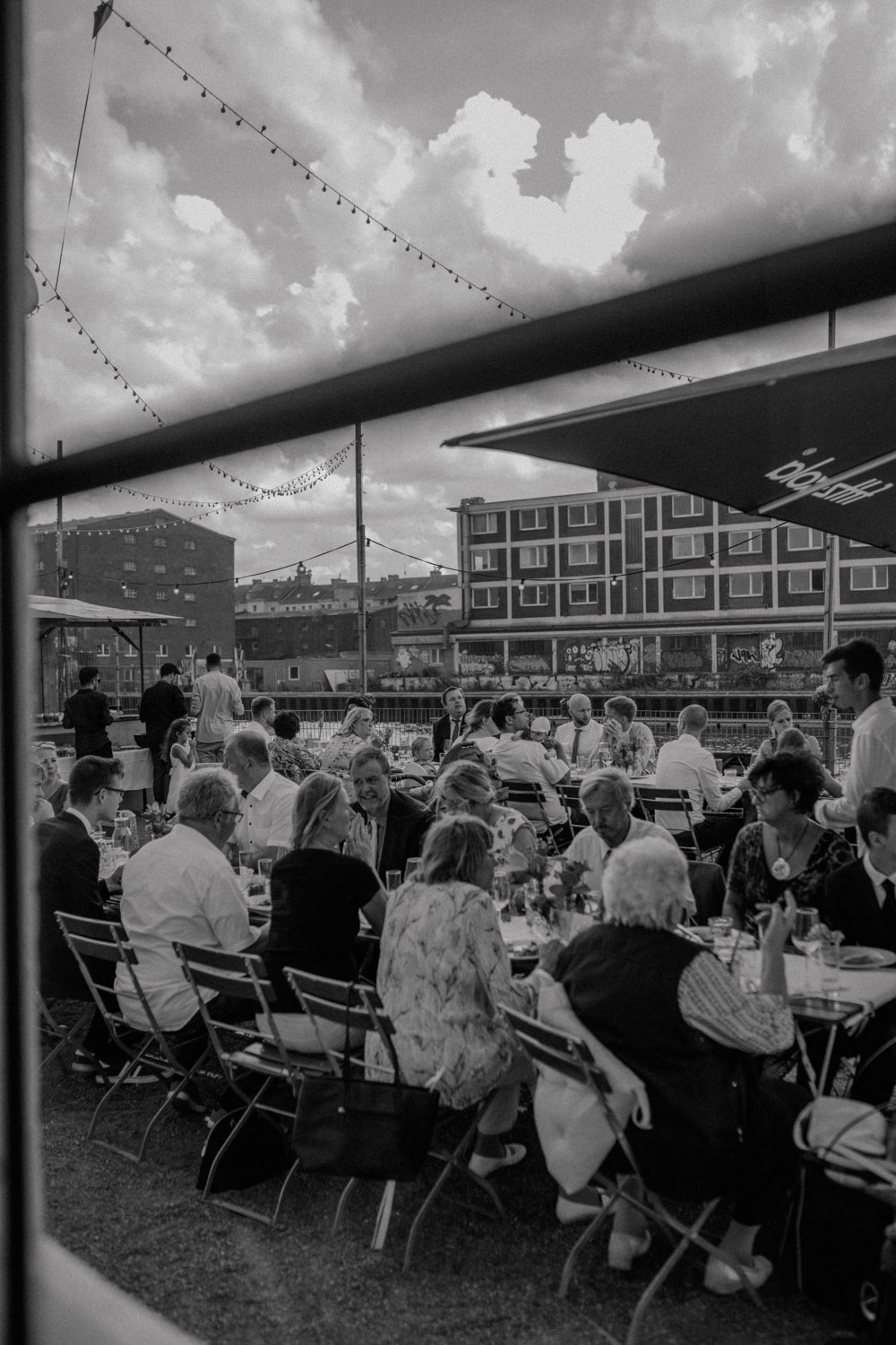 Hochzeitsgäste feiern an langen Tischen draußen