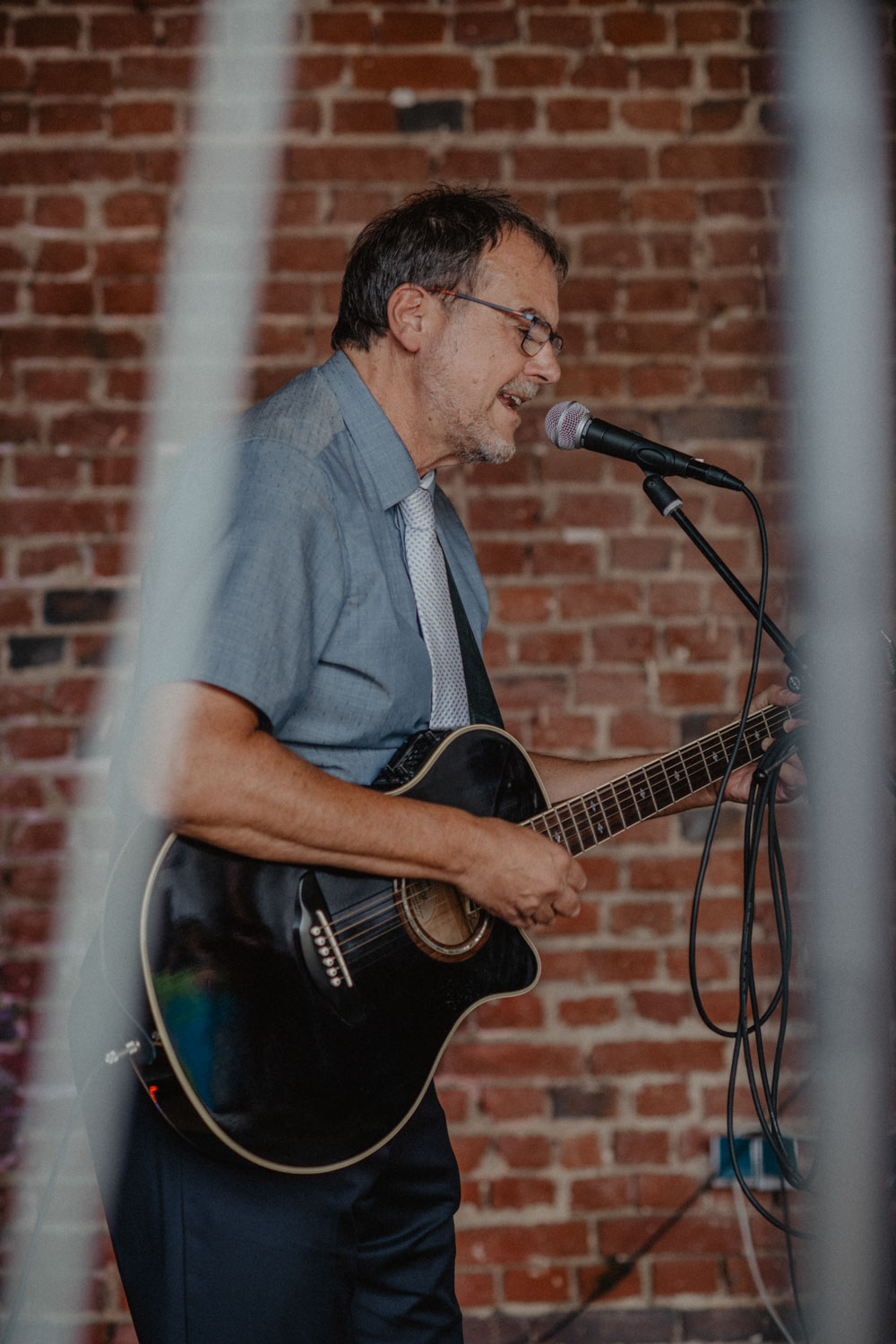 Gitarrist singt auf Hochzeit vor Backsteinwand