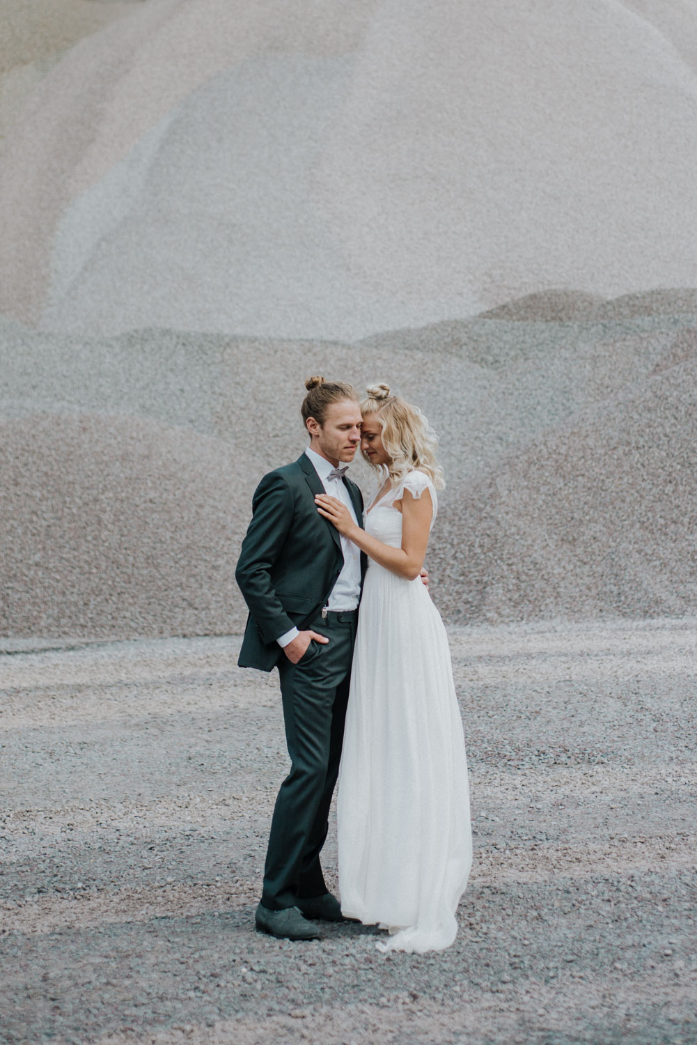 Brautpaar umarmt sich vor grauer NaturkulisseSteinbruch