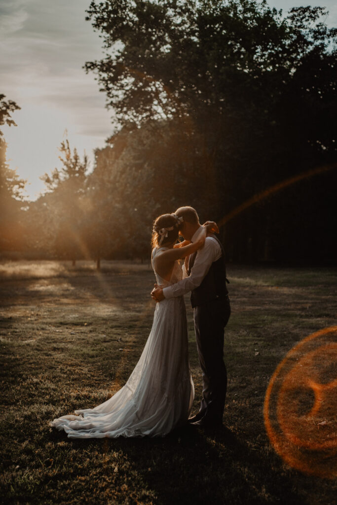Brautpaar umarmt sich im Gegenlicht der Abendsonne