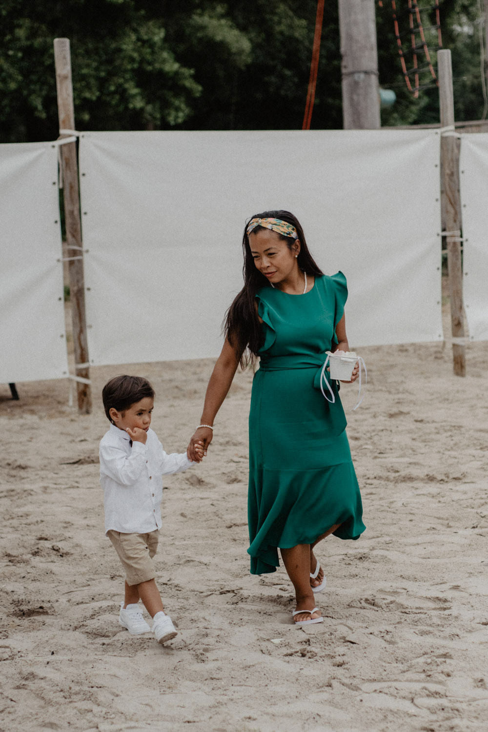 Frau in grünem Kleid mit Kind an der Hand auf dem Weg zur Hochzeit
