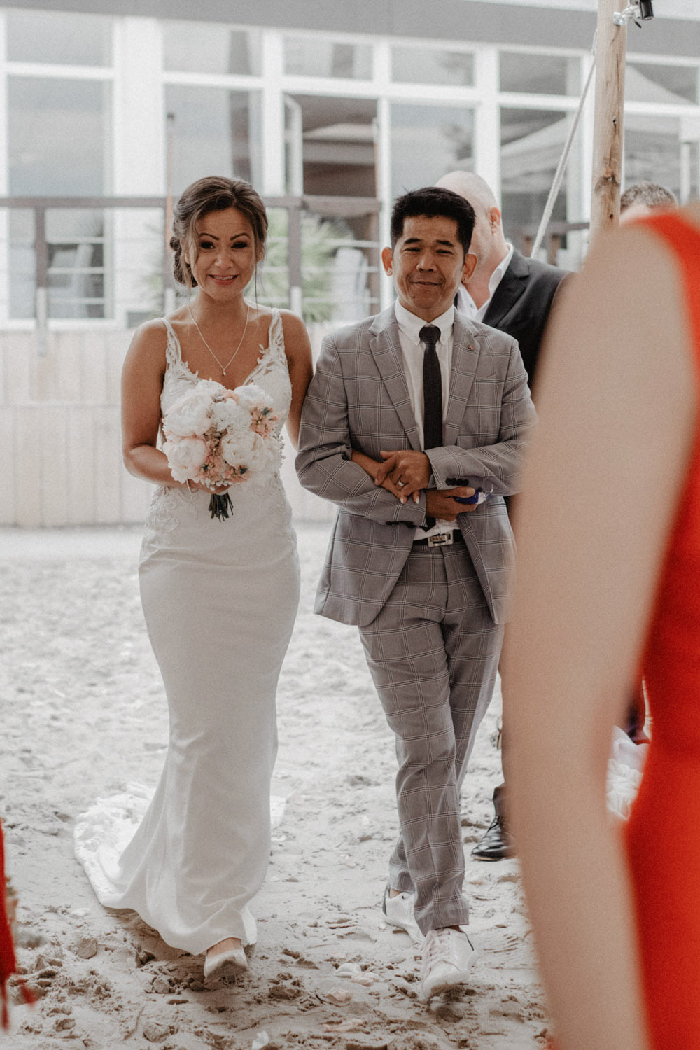 Braut wird von ihrem Vater durch den Sand zum Altar begleitet