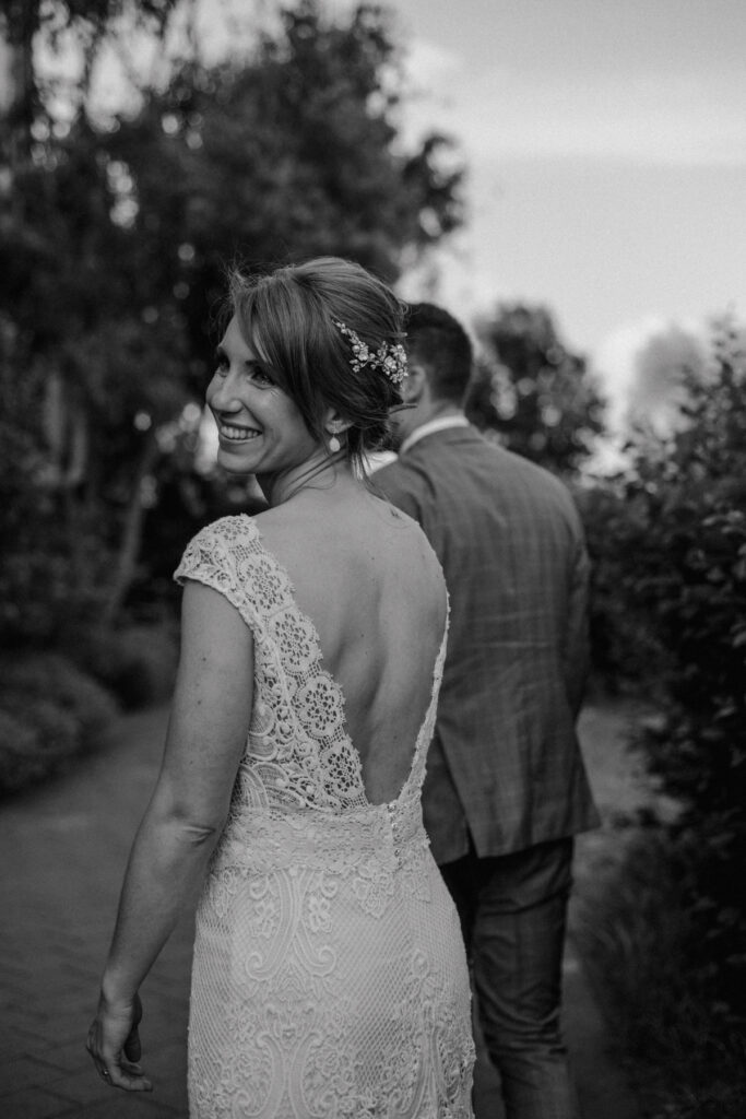 Braut lächelt glücklich über die Schulter während des Spaziergangs