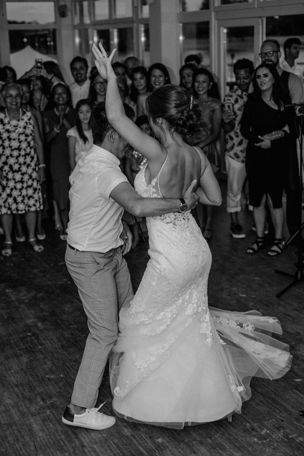 Braut tanzt ausgelassen mit Vater am Seeufer