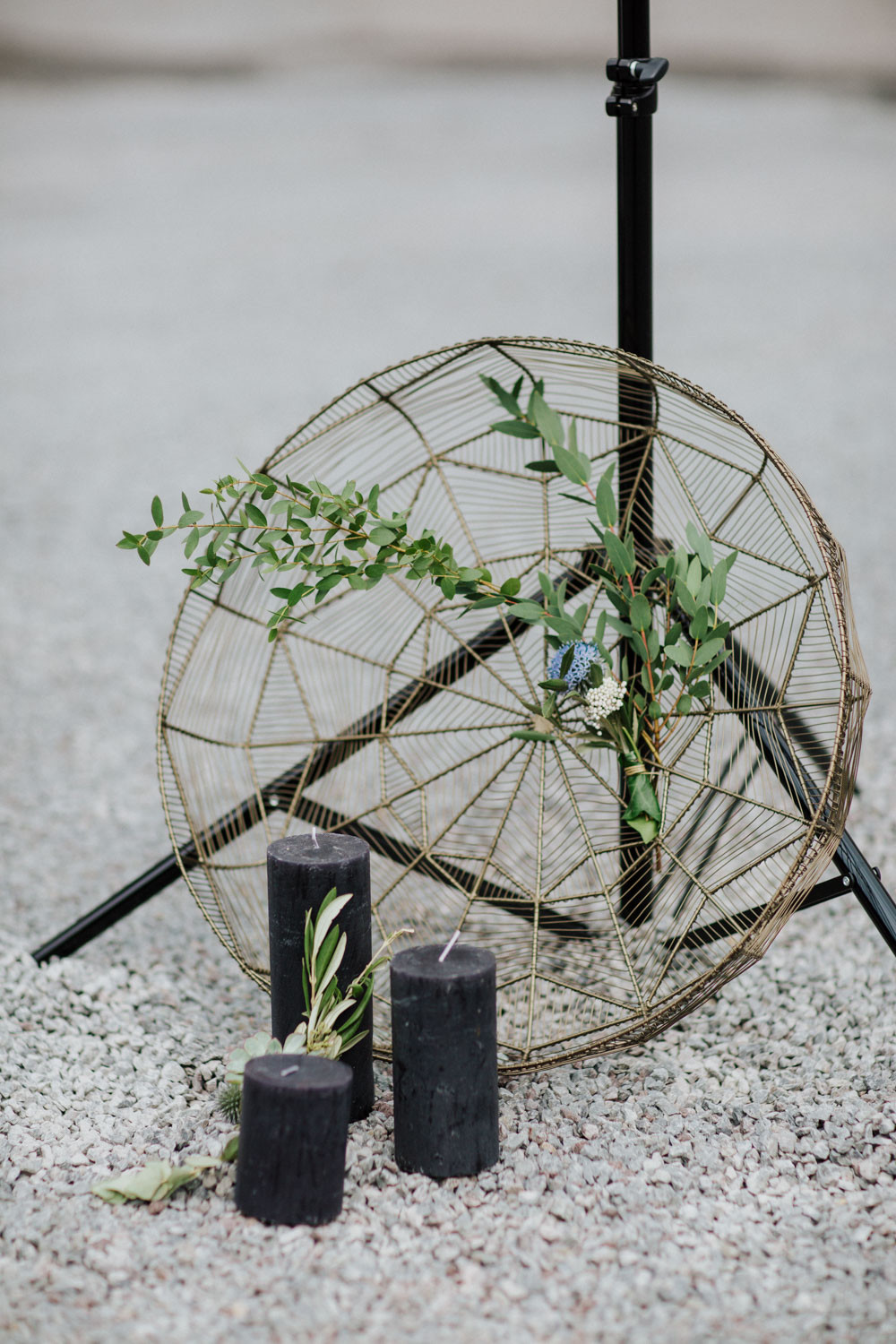 Runde Metall-Deko mit Olivenzweig auf Kiesboden