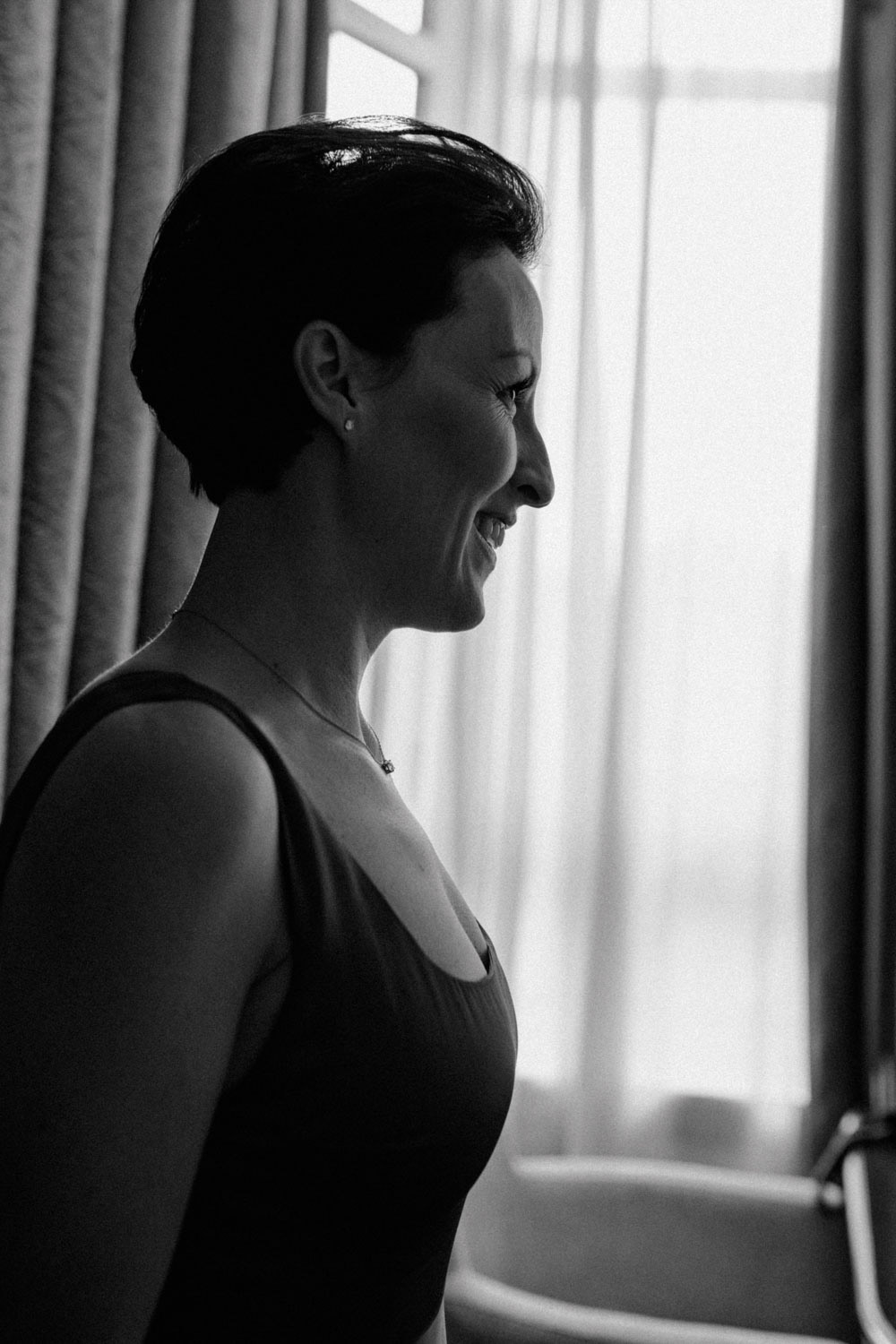 Frau im roten Kleid lächelt beim Getting Ready im Hotelzimmer