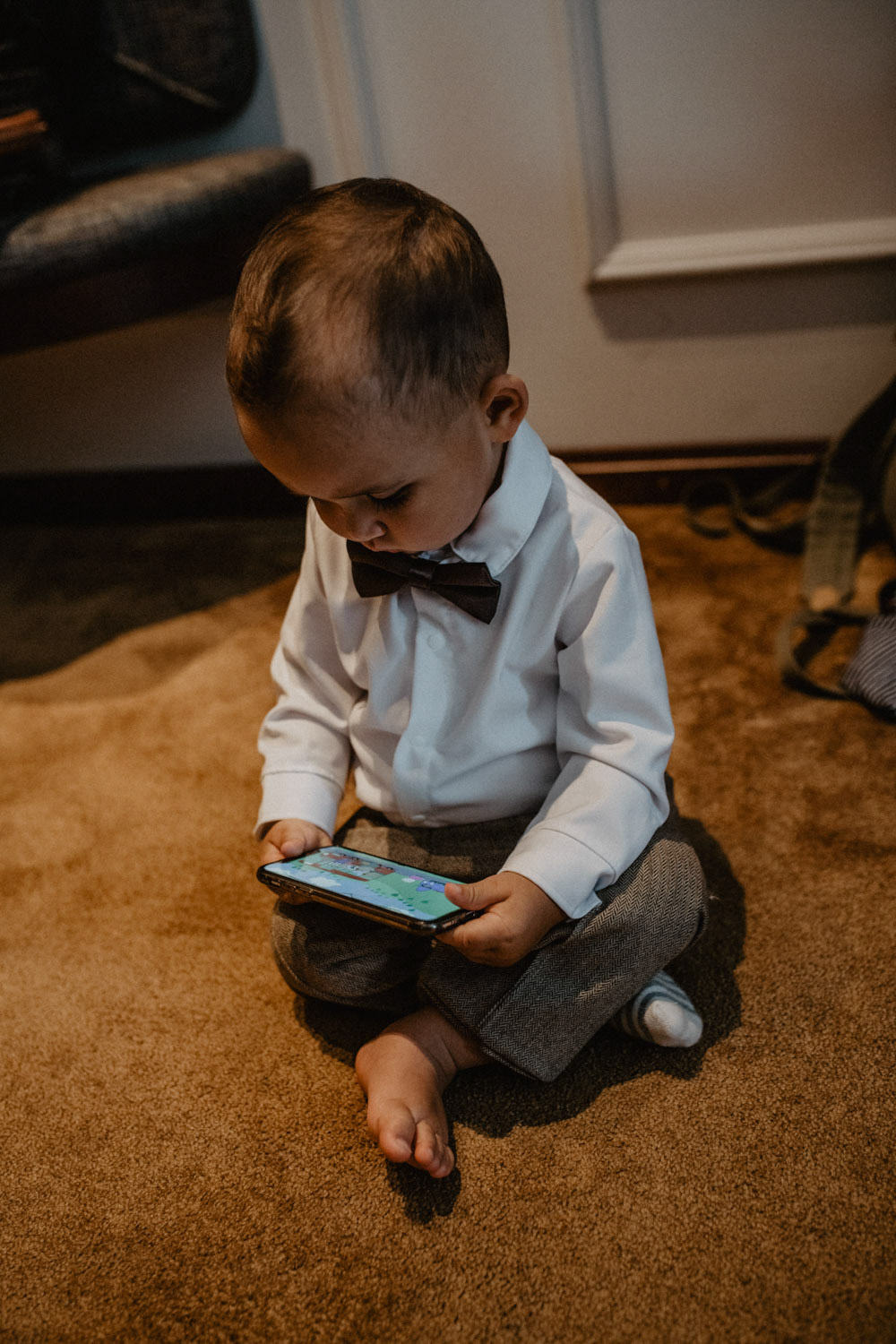 Kind im Anzug schaut auf Handy beim Getting Ready