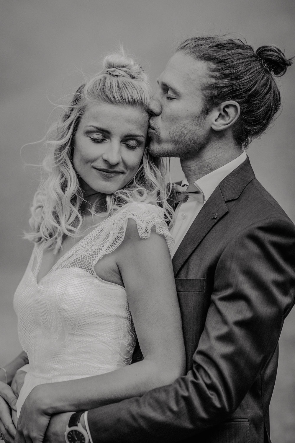 Bräutigam umarmt Braut von hinten in Schwarz-Weiß