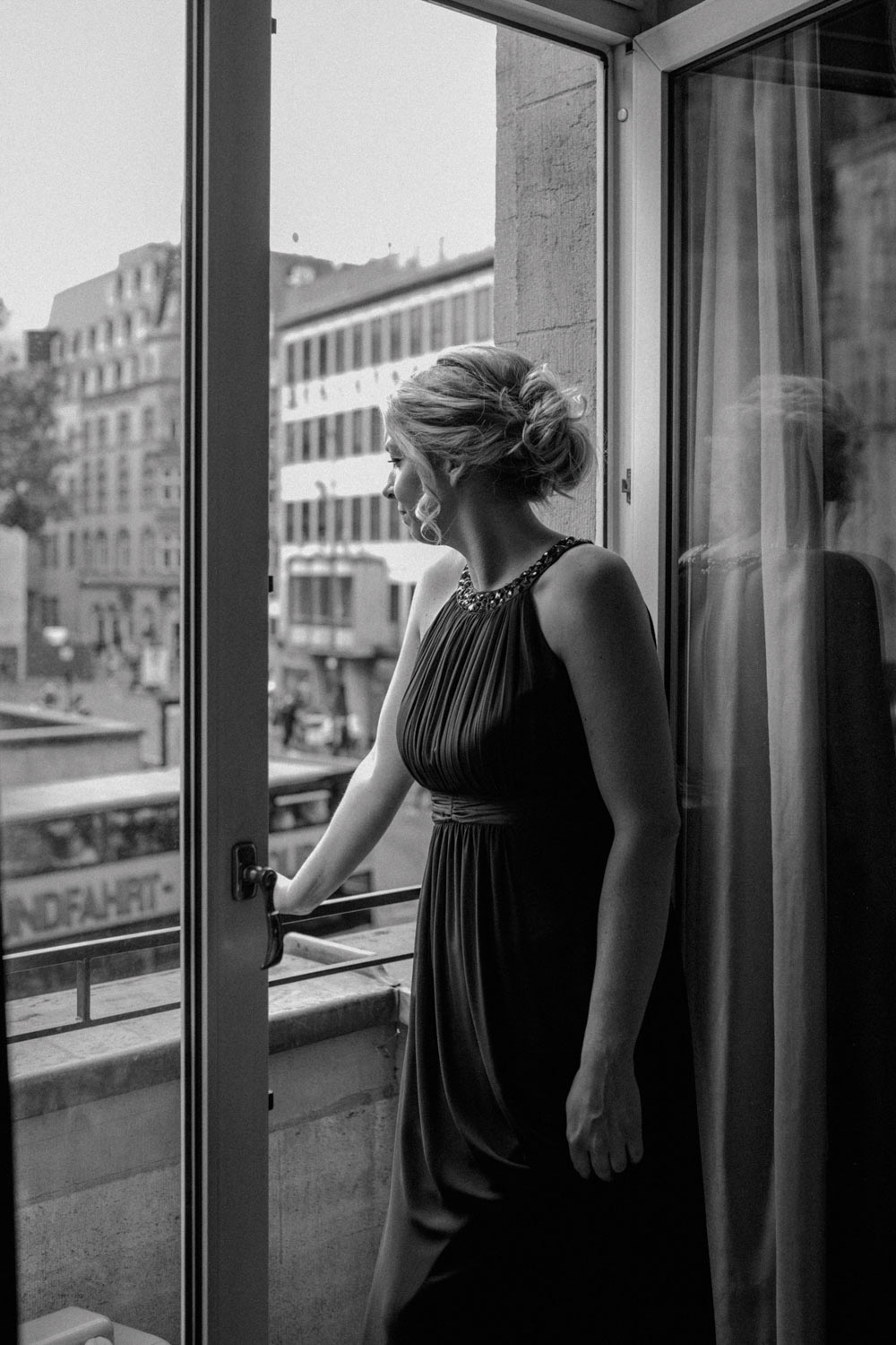 Frau im Abendkleid blickt aus dem Fenster, schwarzweiß