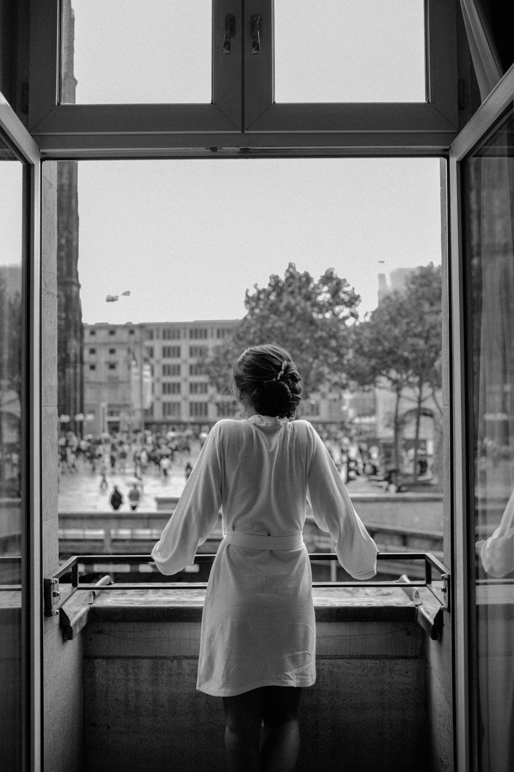 Braut steht im Bademantel am Hotelfenster, schwarzweiß