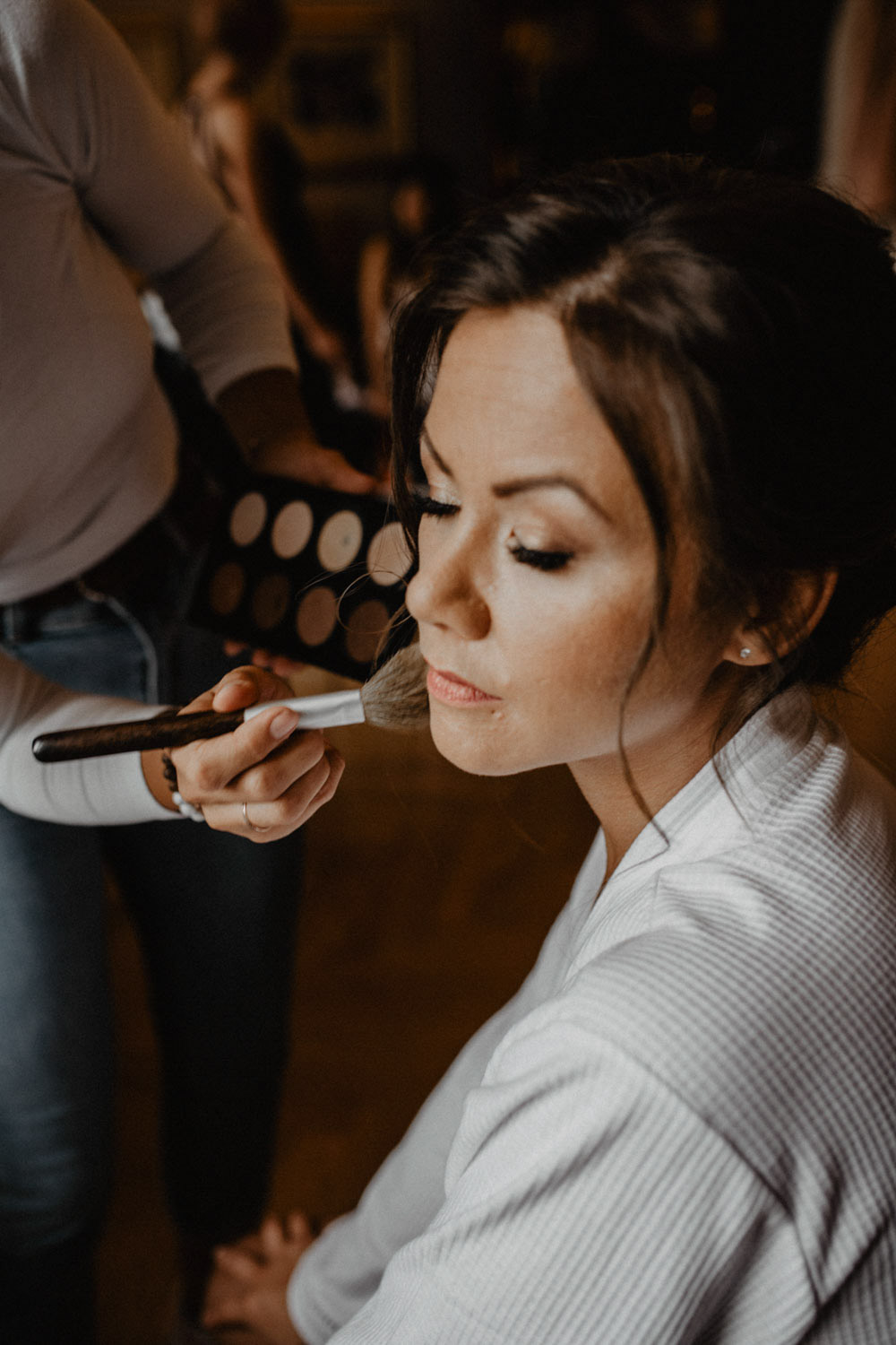 Visagistin schminkt Braut mit Pinsel