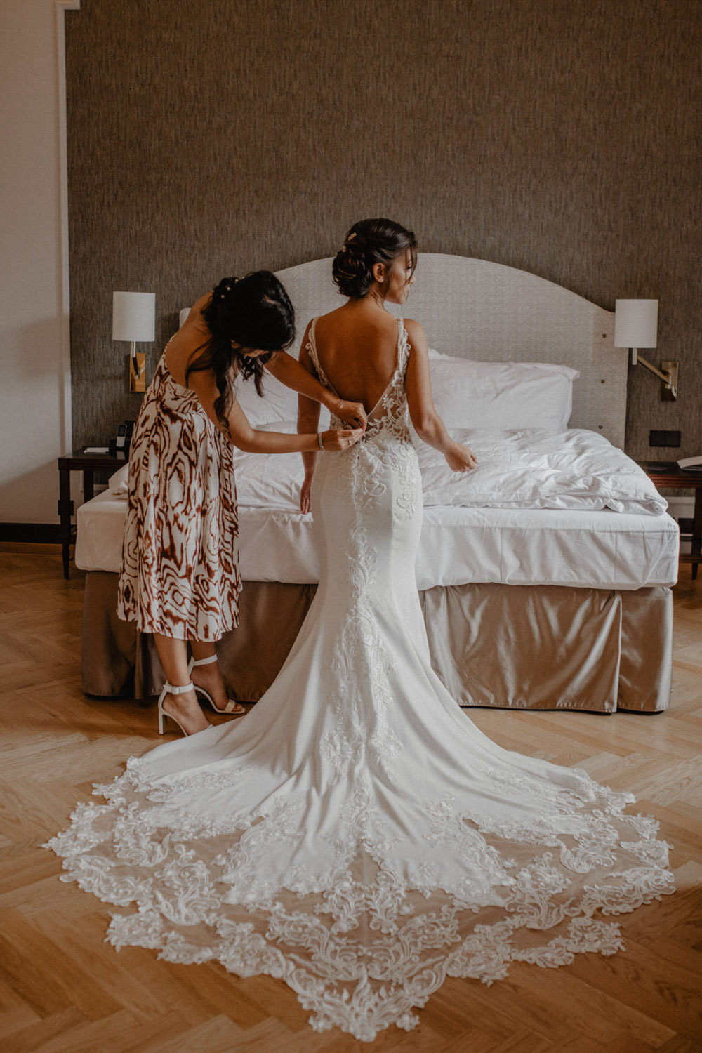 Braut wird beim Ankleiden im Hotelzimmer unterstützt