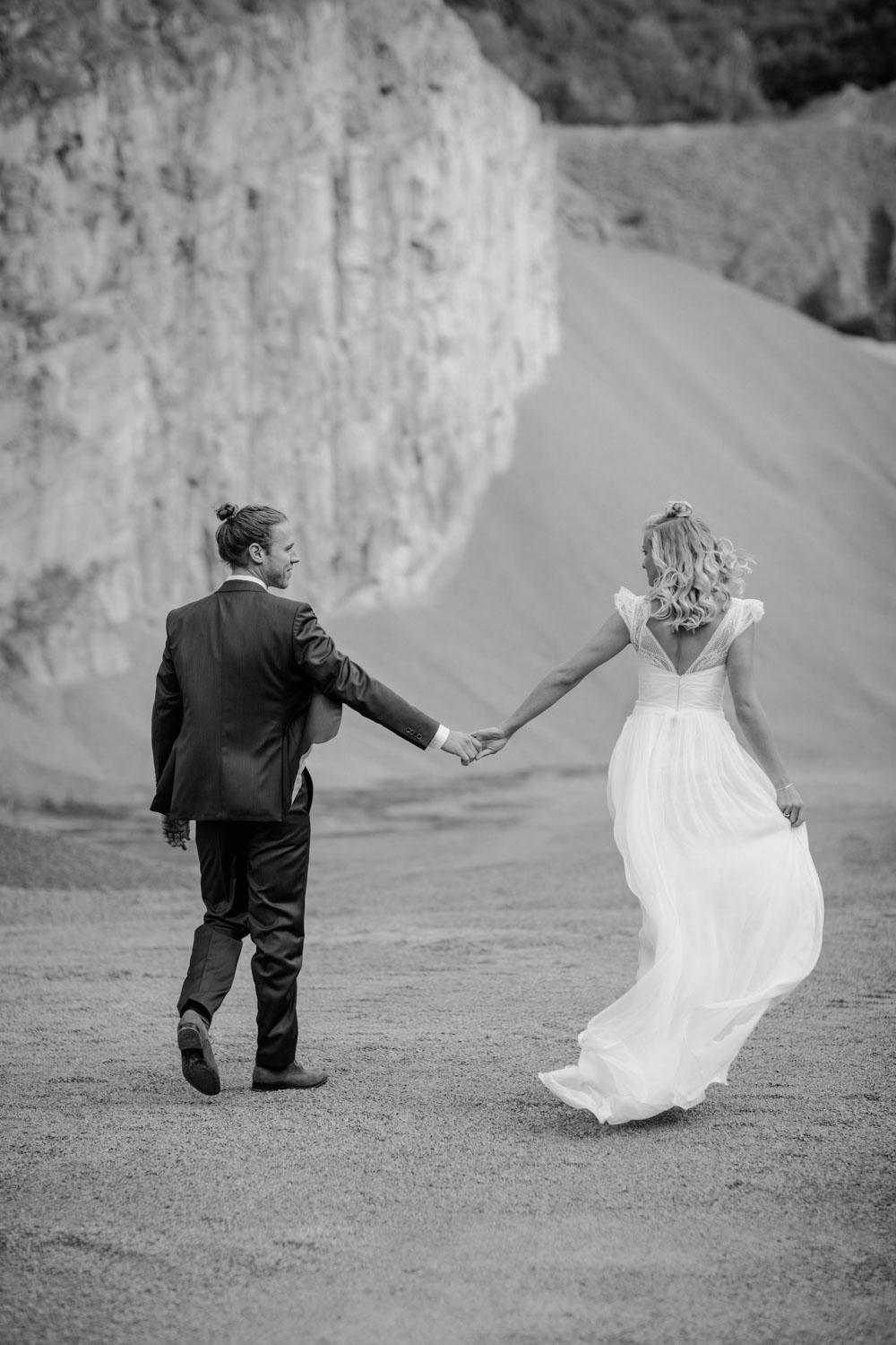Brautpaar läuft gemeinsam Richtung Felswand
