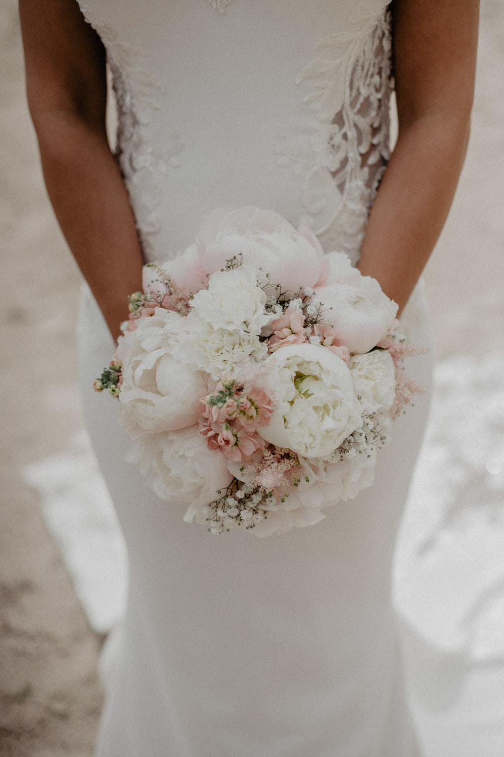 Braut hält romantischen Strauß mit weißen Pfingstrosen