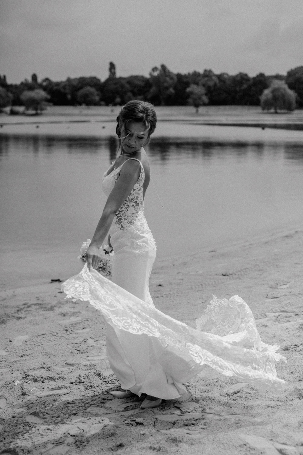 Braut dreht sich am See, hält die Schleppe elegant