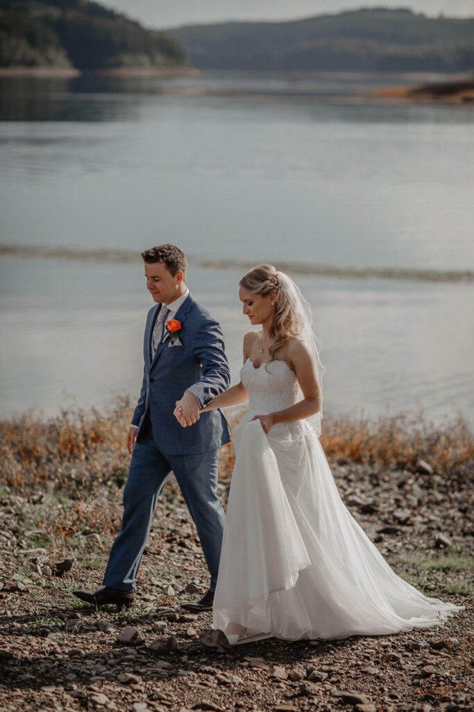 Brautpaar läuft Hand in Hand am Sorpesee