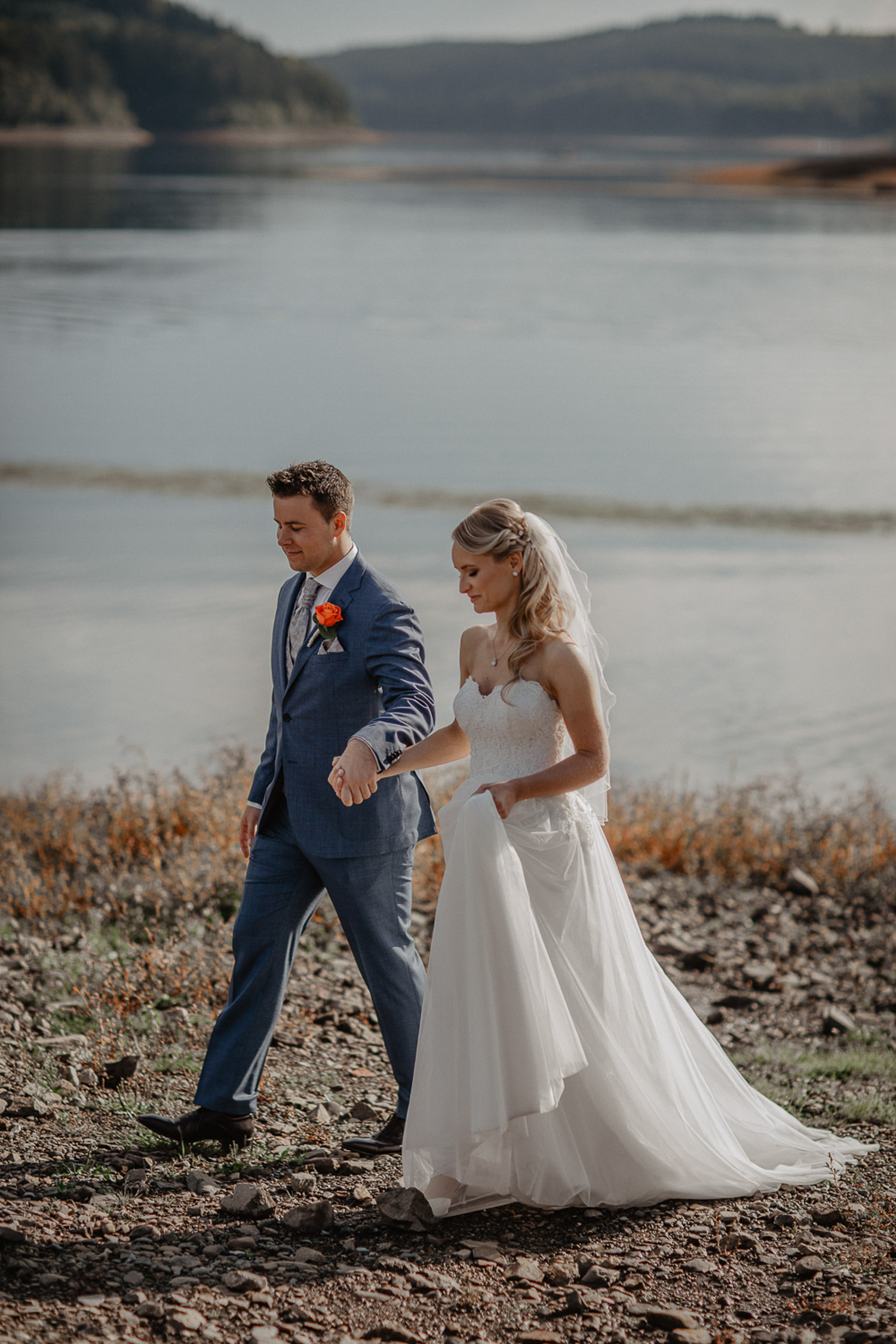 Brautpaar läuft Hand in Hand am Sorpesee