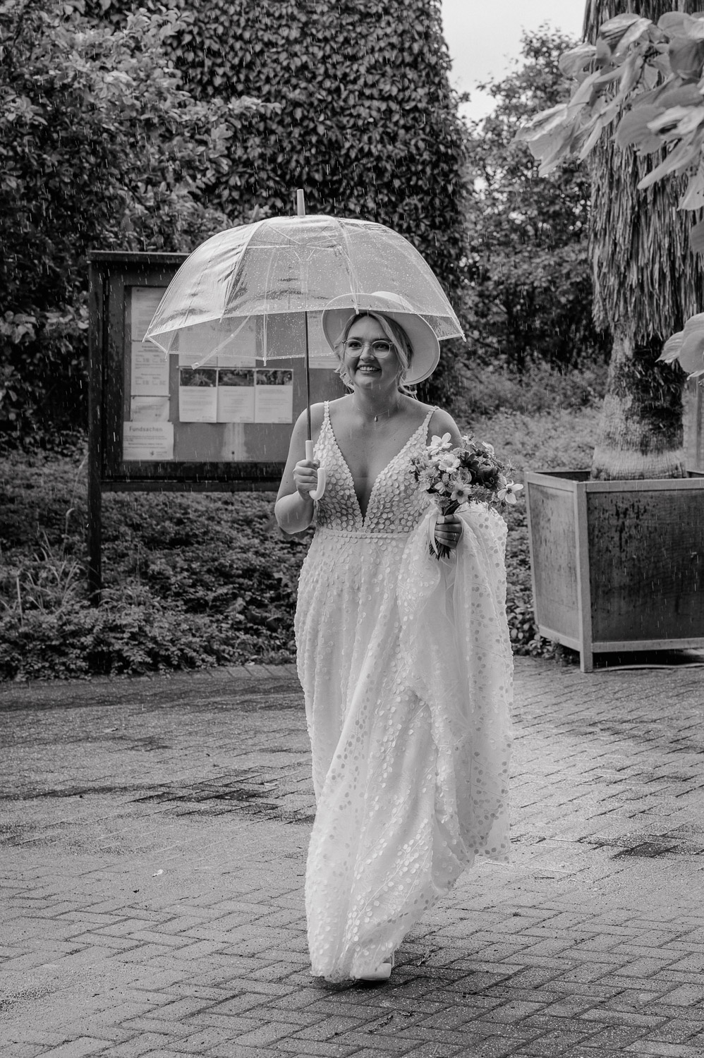 Braut mit Schirm auf dem Weg zur Trauung im Botanischen Garten