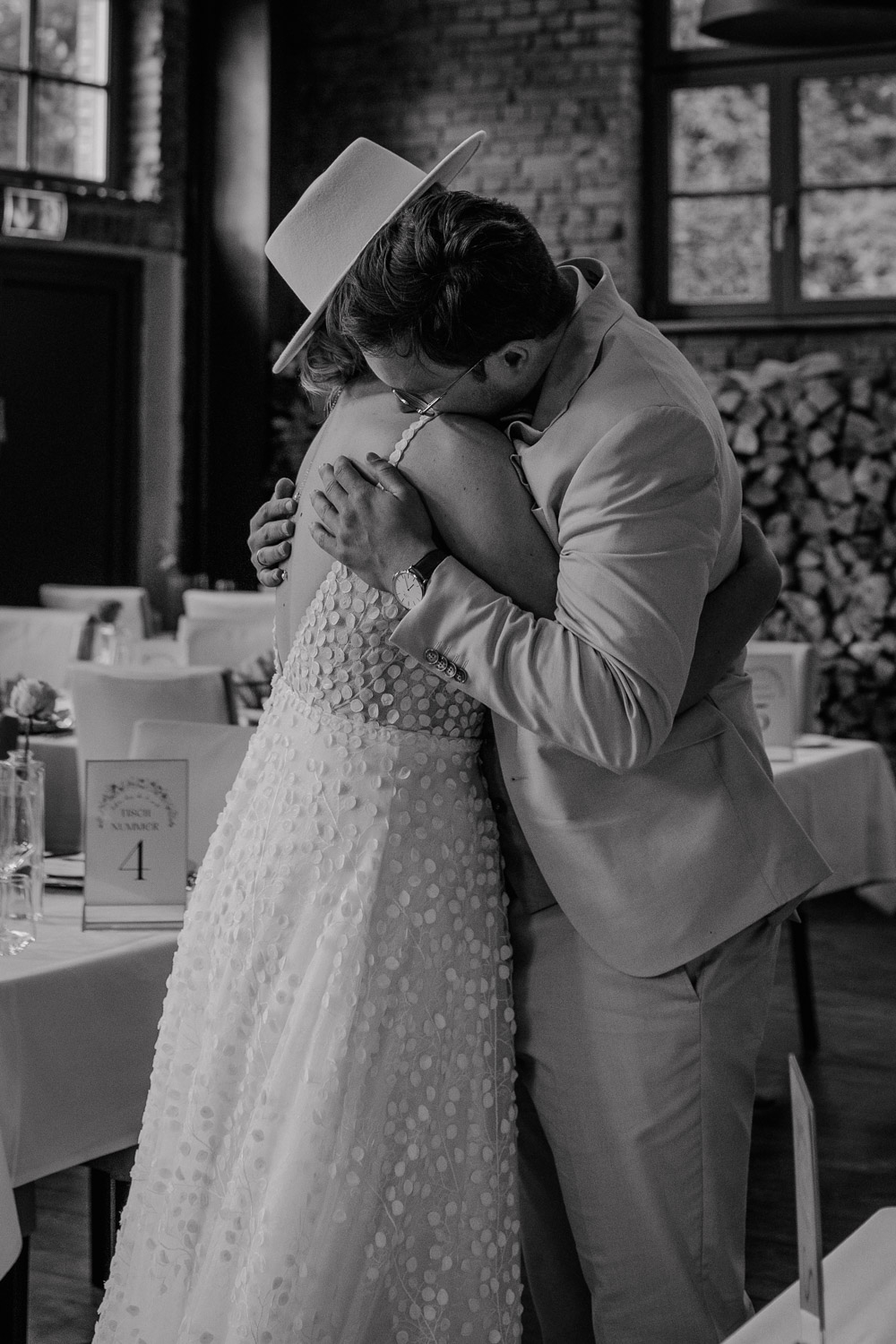 Bräutigam umarmt Braut im Hochzeitssaal