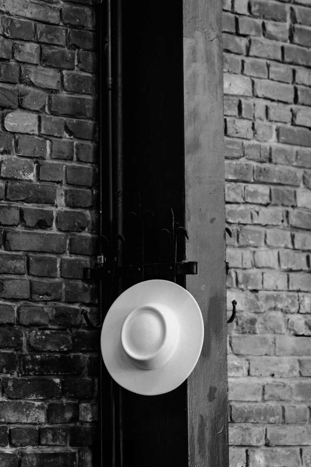 Weißer Boho-Hut hängt an Backsteinwand im Hochzeitssaal