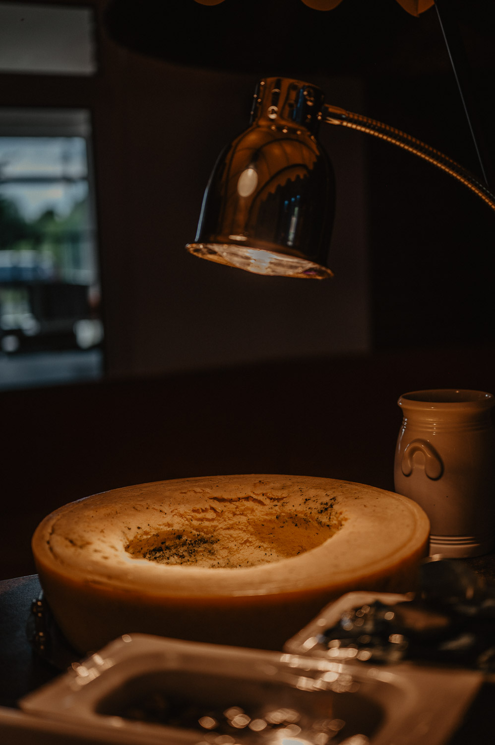 Ausgehöhlter Käselaib unter Wärmelampe beim Hochzeitsessen