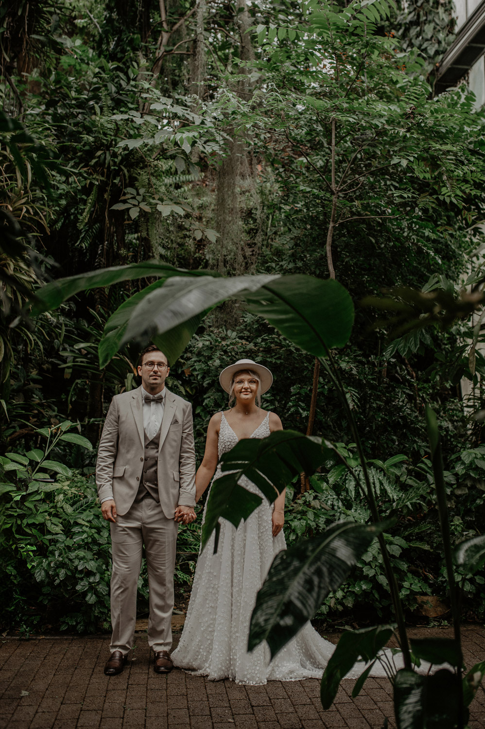 Brautpaar steht ruhig zwischen tropischen Pflanzen