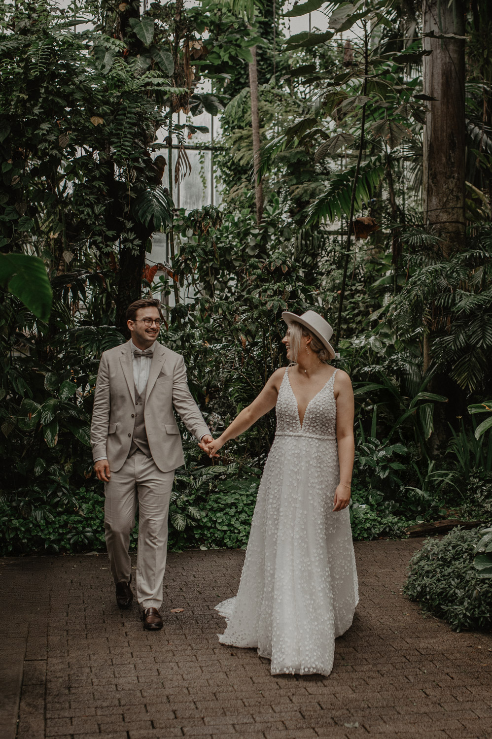 Brautpaar geht lächelnd durch das Tropenhaus