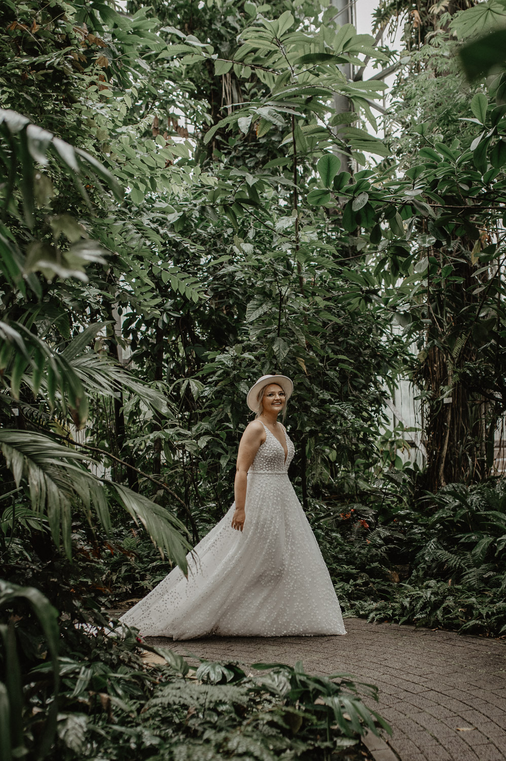 Braut dreht sich lachend im Kleid im Tropenhaus