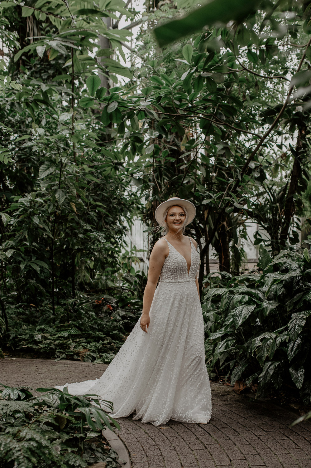Braut spaziert durch das Tropenhaus mit fließendem Kleid