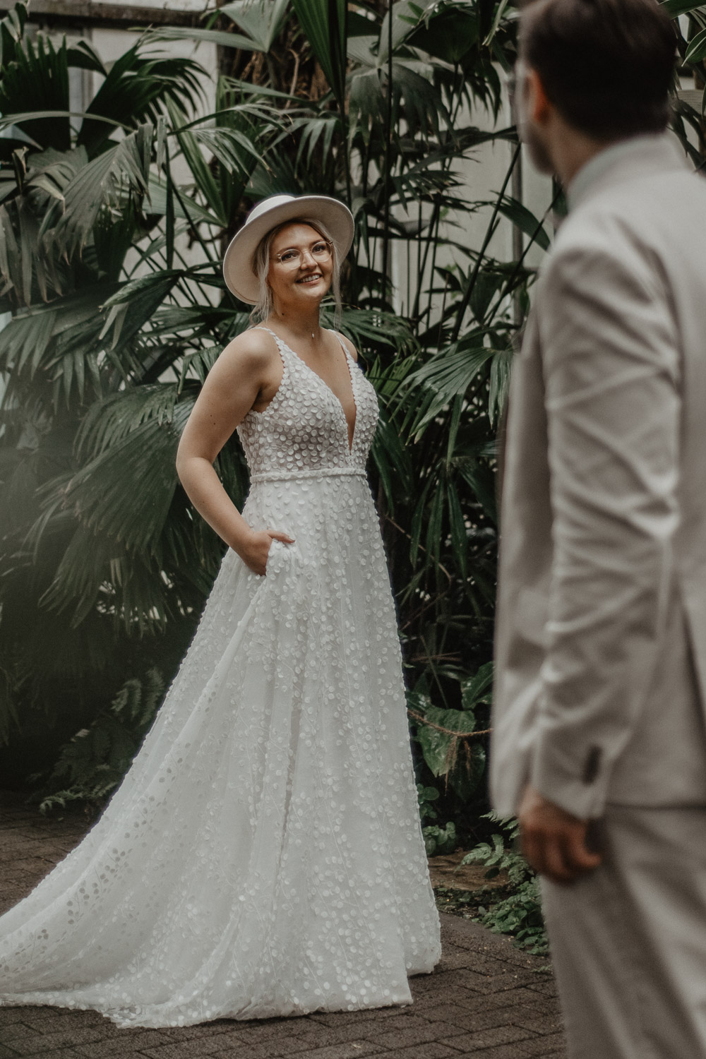 Braut lächelt beim First Look im Tropenhaus ihren Bräutigam an