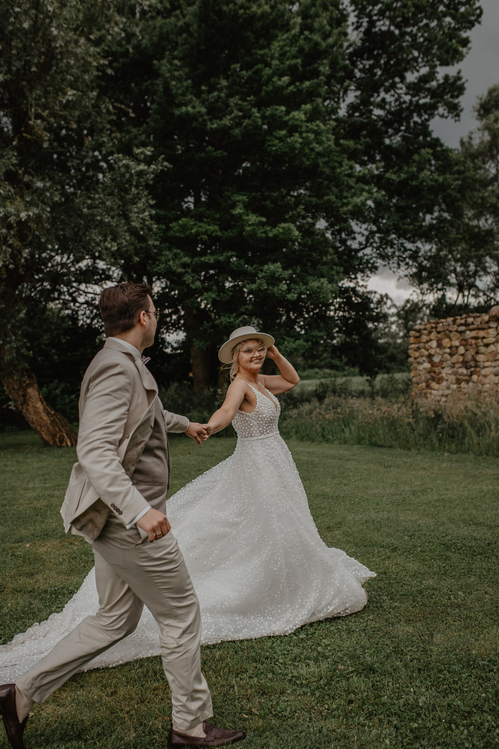 Brautpaar läuft Hand in Hand über grüne Wiese