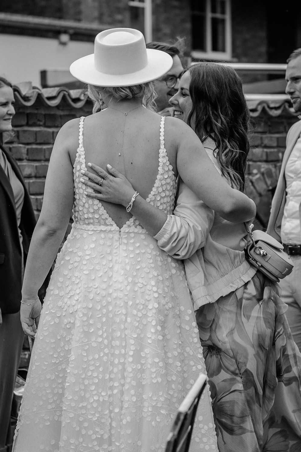 Braut umarmt Freundin herzlich im Innenhof des Beverland