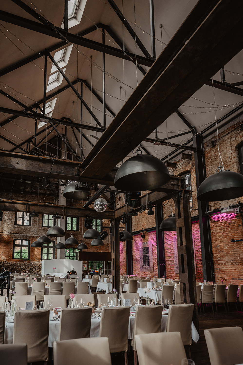 Großer Hochzeitssaal im Industrial Style mit Backstein und Lichterketten