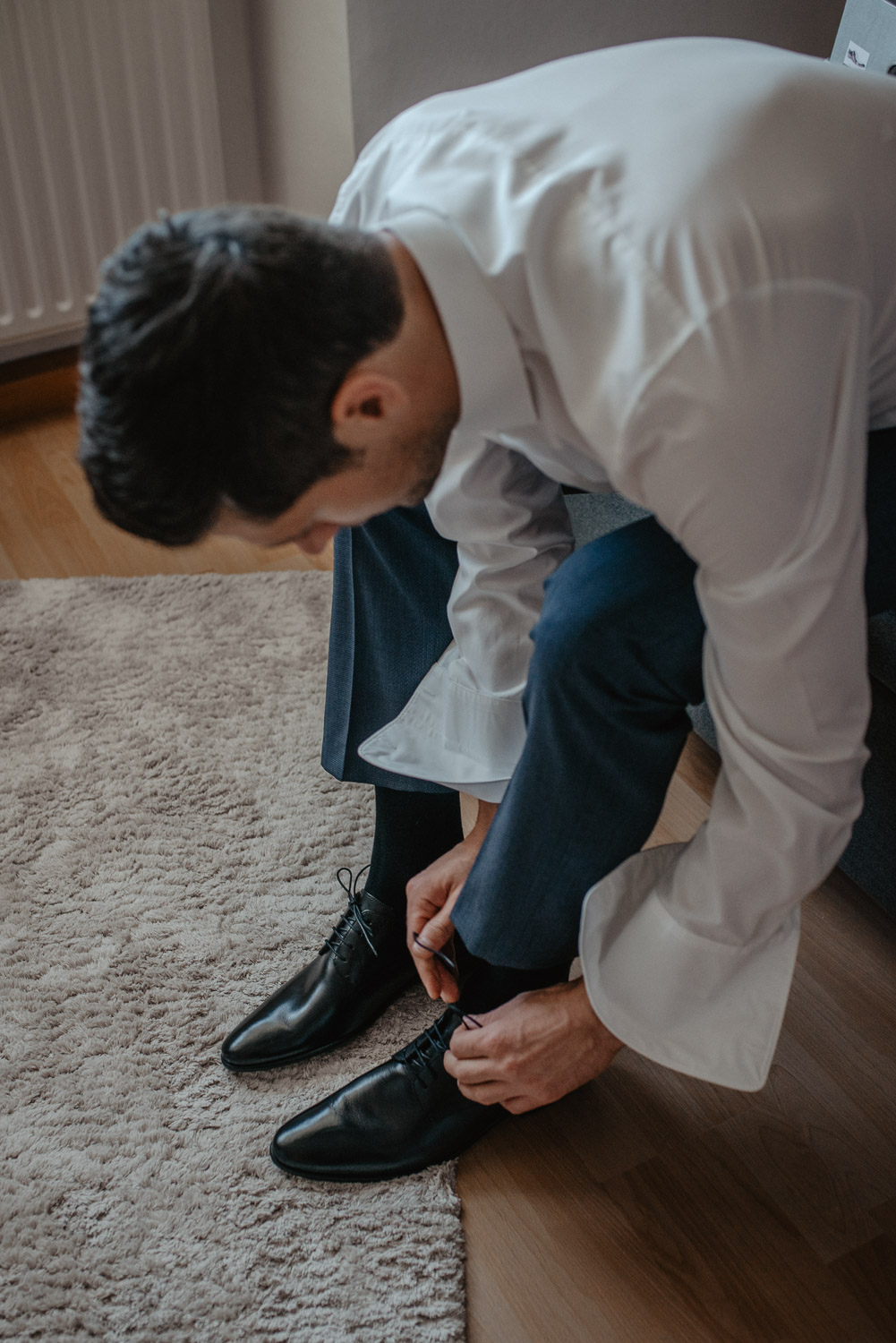 Bräutigam schnürt seine schwarzen Schuhe während des Getting Ready.
