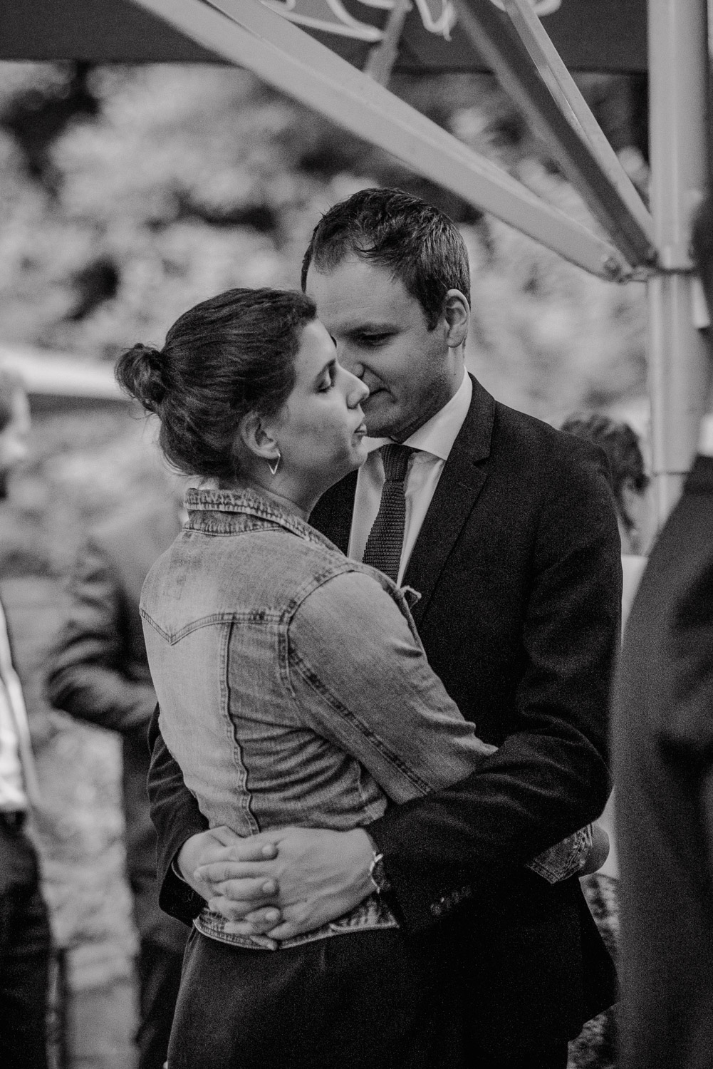 Paar umarmt sich zärtlich draußen beim Empfang der Hochzeitsfeier.