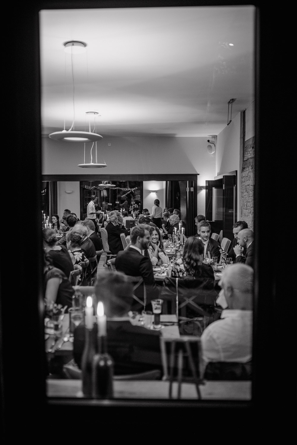 Blick durch ein Fenster in den festlich gedeckten Saal, Schwarz-Weiß.