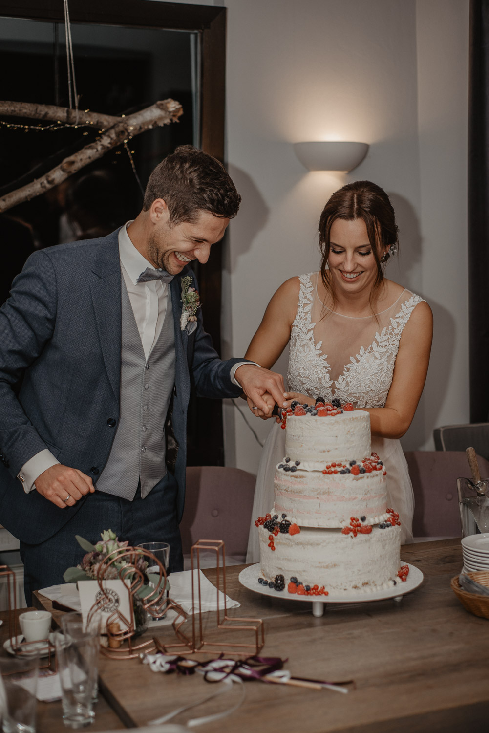 Braut und Bräutigam schneiden gemeinsam die Hochzeitstorte an.