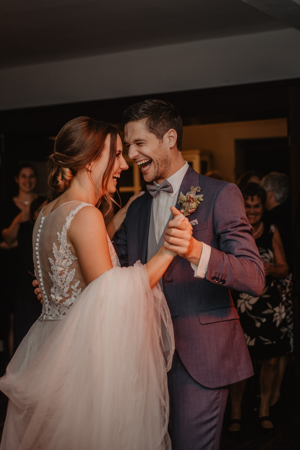 Braut und Bräutigam lachen beim ersten Tanz im Wirtshaus.