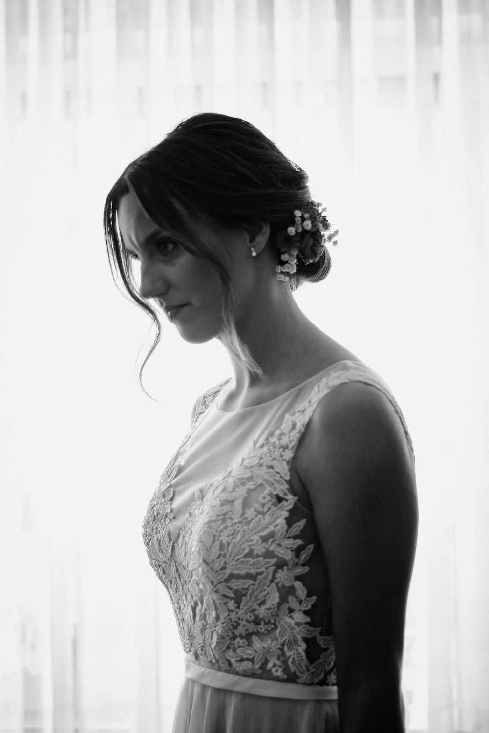 Schwarz-Weiß Porträt der Braut im Hochzeitskleid vor dem Fenster.