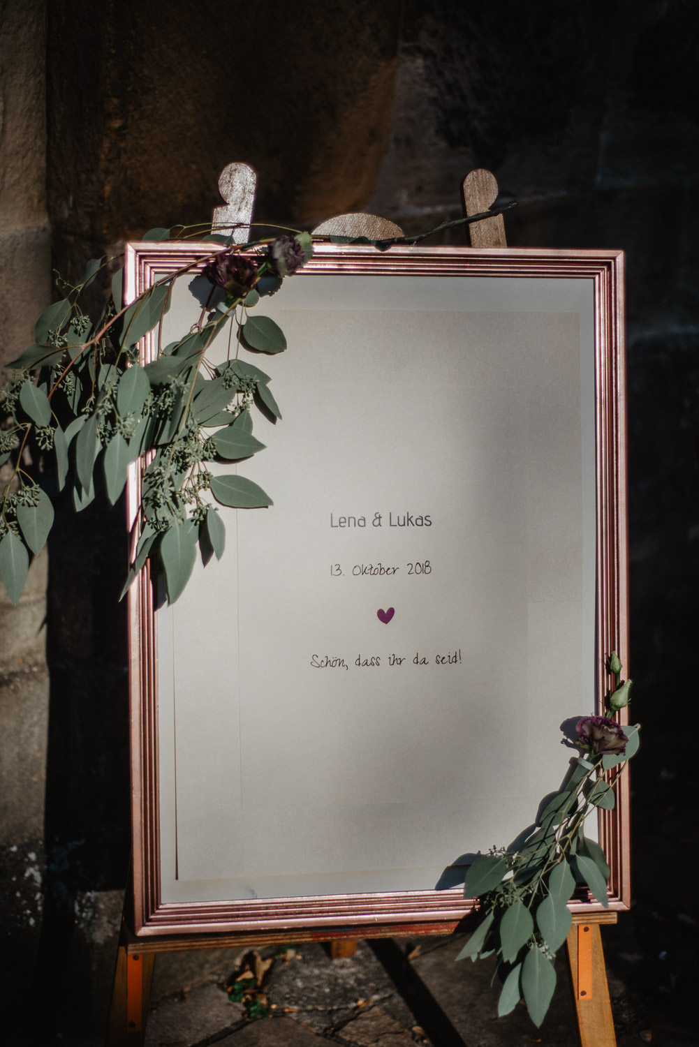 Willkommensschild mit Namen und Hochzeitsdatum vor der Kirche.