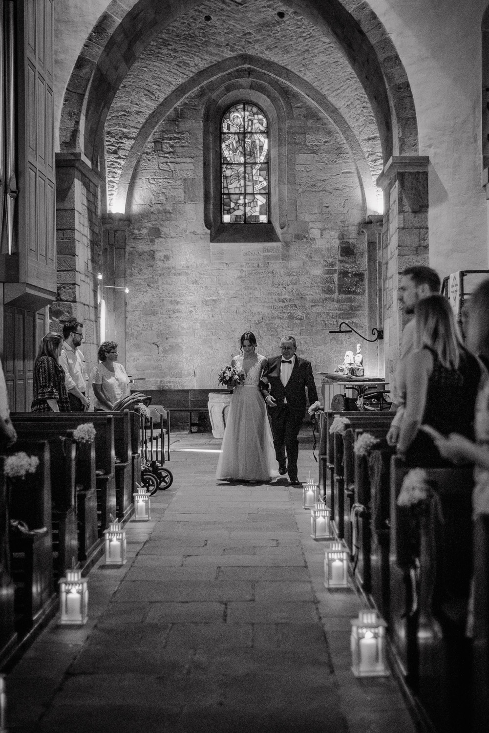 Braut wird von ihrem Vater in die Kirche geführt, Schwarz-Weiß Aufnahme.